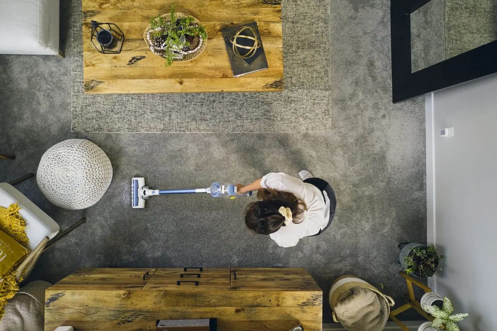 Person vacuuming a carpeted living room.